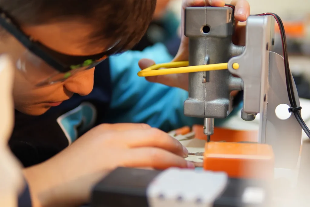 Doku Koleji maker ahşap atölyesinde güvenlik gözlüğüyle matkap kullanan öğrenci